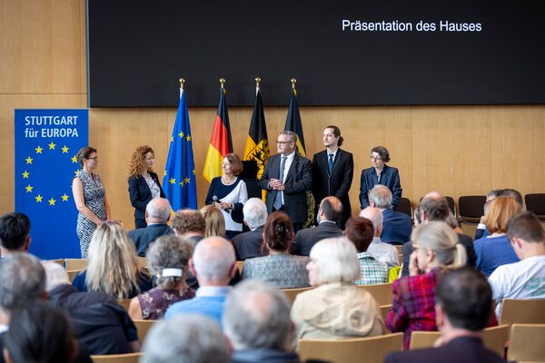 Größere Gruppe von Referenten steht auf der Bühne vor dem Publikum