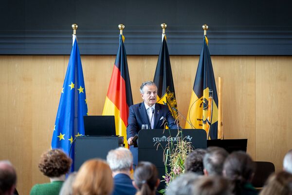 Dr. Frank Nopper am Rednerpult, hinter ihm eine Reihe verschiedener Fahnen